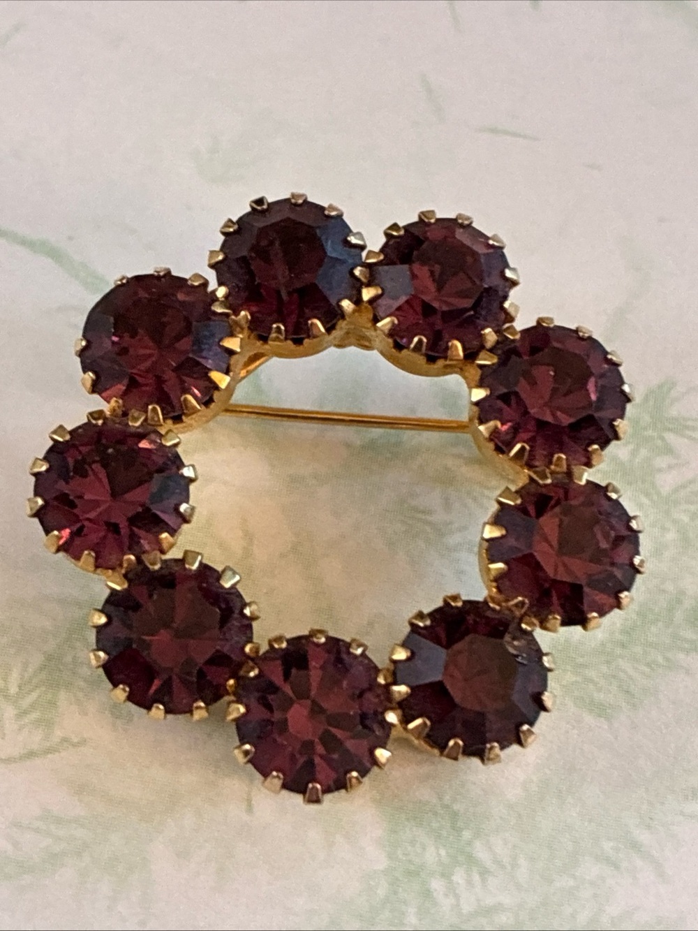 Vintage wreath brooch with deep amethyst colored rhinestones set in gold tone